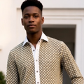 Man wearing a patterned shirt and white pants standing outdoors.